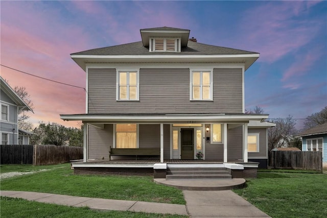 traditional style home featuring covered porch, a yard, and fence