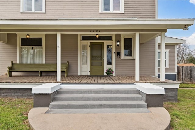 entrance to property with a porch and fence