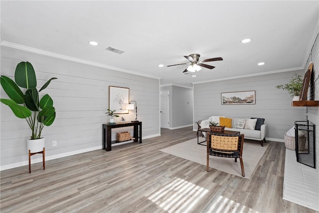 living room featuring light hardwood / wood-style flooring, ornamental molding, and ceiling fan