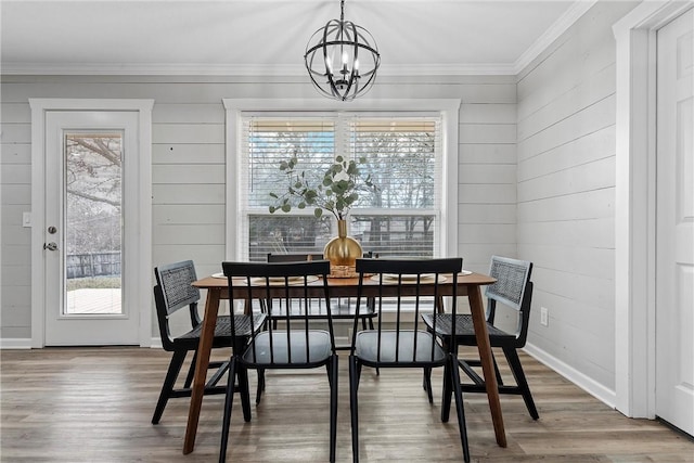 dining space with hardwood / wood-style flooring, crown molding, an inviting chandelier, and a wealth of natural light