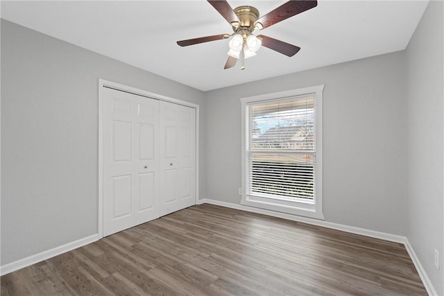 unfurnished bedroom with dark wood-type flooring, ceiling fan, and a closet