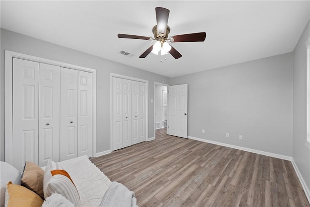 interior space featuring two closets, ceiling fan, and light wood-type flooring