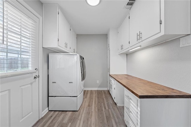 laundry room featuring washer / dryer, light hardwood / wood-style floors, and cabinets