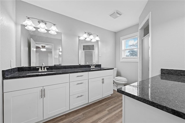 bathroom featuring hardwood / wood-style flooring, vanity, an enclosed shower, and toilet