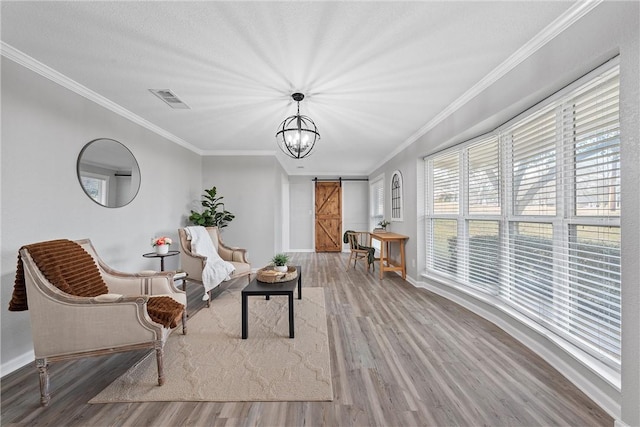 living area featuring ornamental molding, a barn door, and light hardwood / wood-style flooring