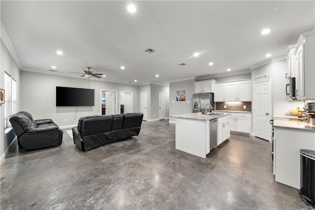 kitchen with light stone counters, appliances with stainless steel finishes, a kitchen island with sink, and white cabinets