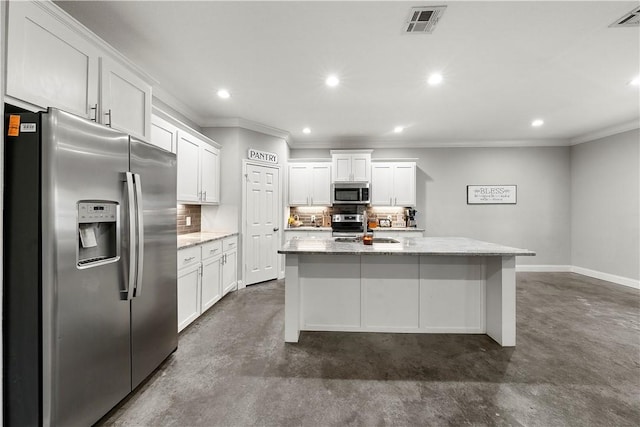 kitchen with appliances with stainless steel finishes, white cabinetry, backsplash, light stone countertops, and an island with sink