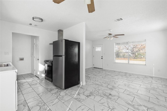 kitchen featuring electric stove, stainless steel fridge, ceiling fan, and a textured ceiling