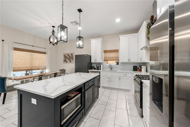 kitchen with white cabinetry, hanging light fixtures, a wealth of natural light, black appliances, and a kitchen island