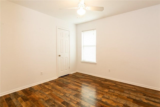 spare room with ceiling fan, dark wood-type flooring, and baseboards