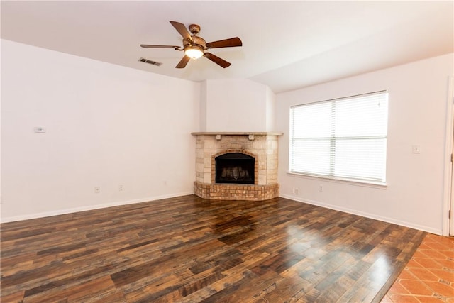 unfurnished living room with a ceiling fan, wood finished floors, visible vents, baseboards, and a fireplace