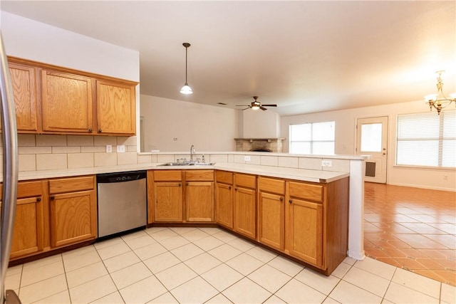 kitchen with a peninsula, a sink, decorative backsplash, light countertops, and dishwasher