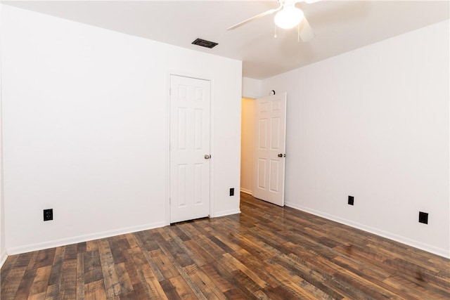 spare room featuring visible vents, baseboards, ceiling fan, and dark wood-style flooring