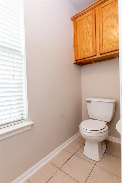 bathroom with baseboards, toilet, and tile patterned flooring