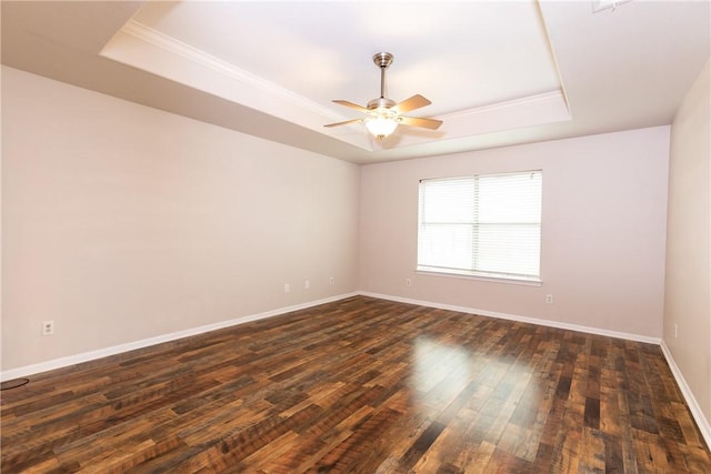 unfurnished room with a ceiling fan, a tray ceiling, dark wood-style floors, and baseboards