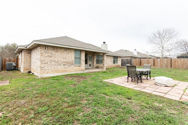 rear view of house with brick siding, central air condition unit, a lawn, a fenced backyard, and a patio