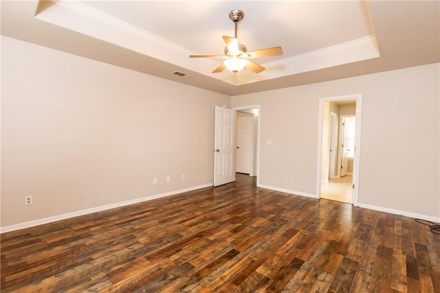 spare room with a tray ceiling, dark wood-style floors, and visible vents