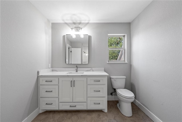 bathroom with toilet, vanity, and tile patterned flooring