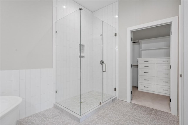 bathroom featuring tile patterned floors, a shower with shower door, and tile walls