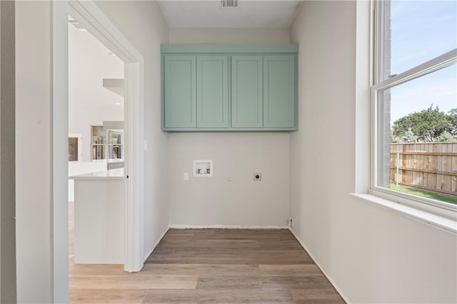 laundry room with light hardwood / wood-style floors, hookup for a washing machine, cabinets, and electric dryer hookup