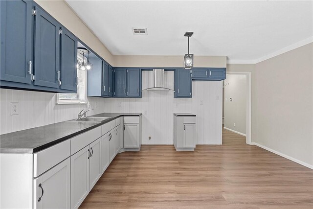 kitchen with light hardwood / wood-style floors, sink, wall chimney range hood, and blue cabinetry