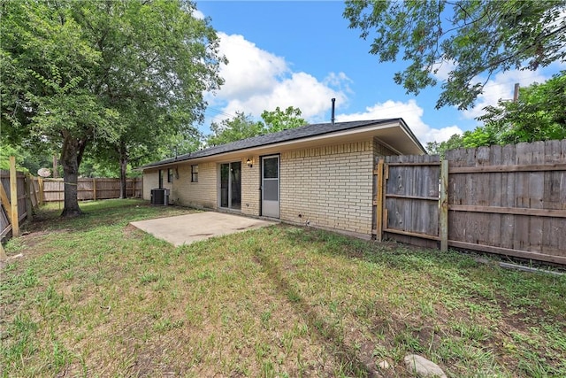 back of house with central AC, a patio area, and a lawn