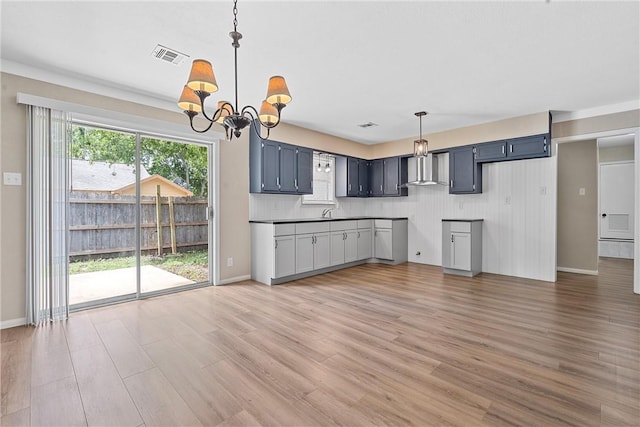 kitchen with wall chimney range hood, sink, hanging light fixtures, hardwood / wood-style flooring, and a chandelier