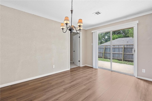 unfurnished dining area with crown molding, a notable chandelier, and hardwood / wood-style flooring