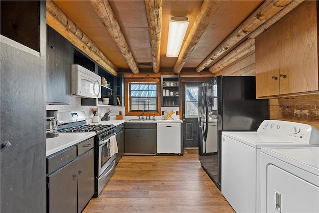 kitchen with sink, washer and dryer, hardwood / wood-style flooring, white appliances, and beam ceiling