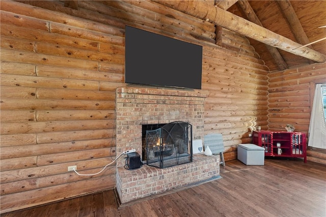 unfurnished living room featuring vaulted ceiling with beams, hardwood / wood-style flooring, a fireplace, and log walls