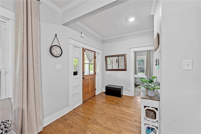 foyer featuring plenty of natural light, ornamental molding, light wood-type flooring, and baseboards