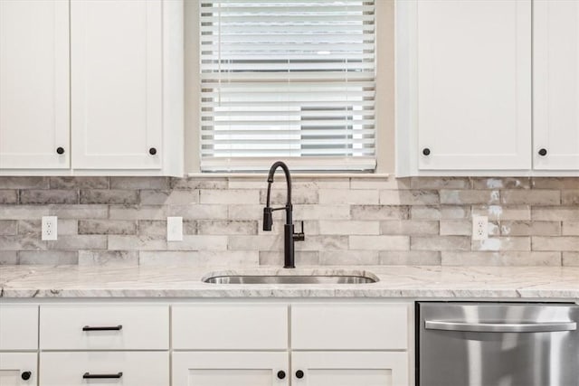 kitchen featuring stainless steel dishwasher, white cabinets, light stone countertops, and sink