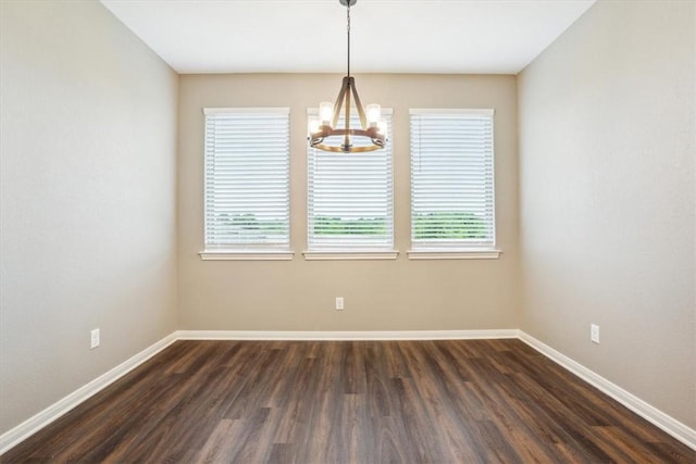 unfurnished room featuring dark hardwood / wood-style floors, a wealth of natural light, and an inviting chandelier