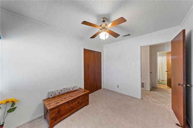 bedroom featuring ceiling fan, light colored carpet, a closet, and a textured ceiling