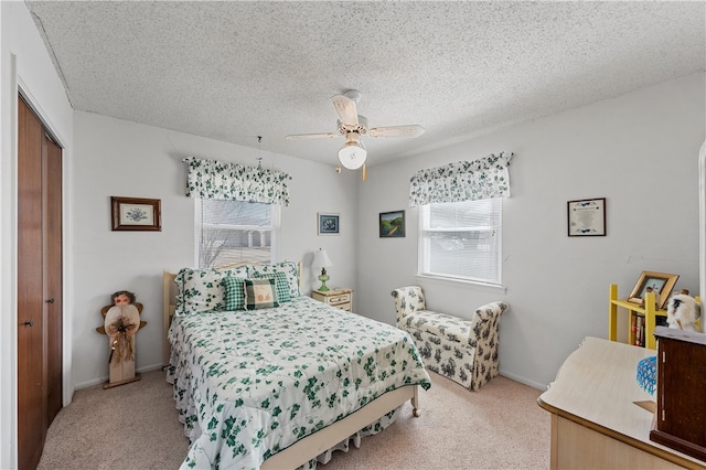 bedroom featuring ceiling fan, light colored carpet, a closet, and a textured ceiling