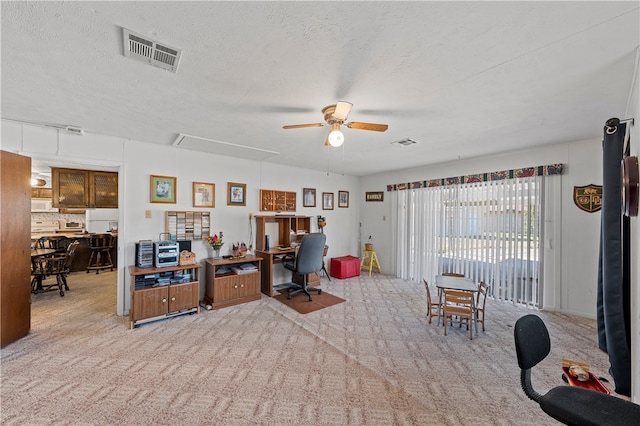 interior space featuring ceiling fan, light colored carpet, and a textured ceiling