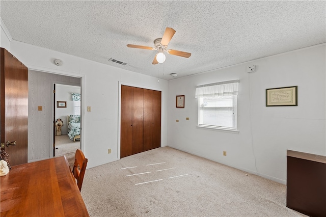 carpeted bedroom featuring ceiling fan, a closet, and a textured ceiling