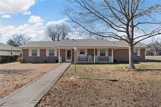 ranch-style home featuring covered porch and a front lawn