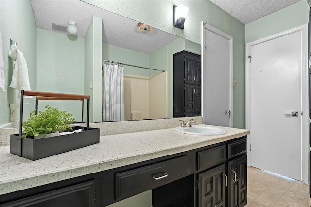 bathroom with tile patterned floors, vanity, a textured ceiling, and walk in shower