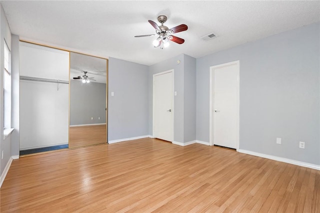 unfurnished bedroom with ceiling fan, a closet, a textured ceiling, and light wood-type flooring