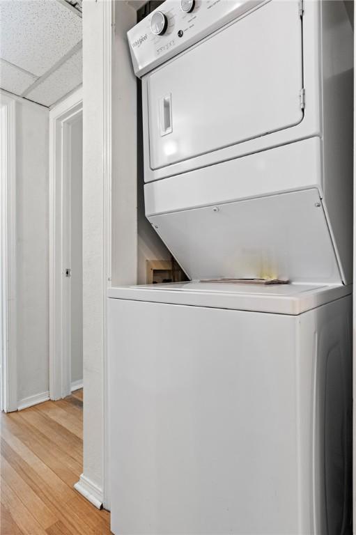 clothes washing area with stacked washing maching and dryer and light hardwood / wood-style floors