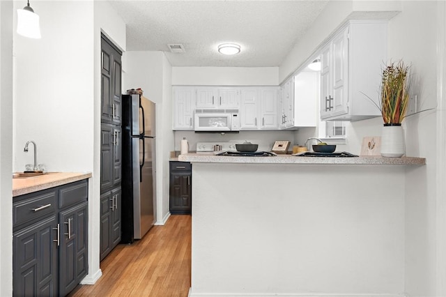 kitchen featuring pendant lighting, white cabinets, stainless steel fridge, a textured ceiling, and light hardwood / wood-style floors