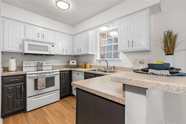 kitchen with a textured ceiling, white appliances, sink, light hardwood / wood-style floors, and white cabinetry