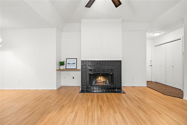 unfurnished living room with hardwood / wood-style flooring, ceiling fan, a fireplace, and a textured ceiling