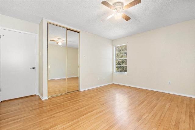 unfurnished bedroom with a textured ceiling, light wood-type flooring, a closet, and ceiling fan