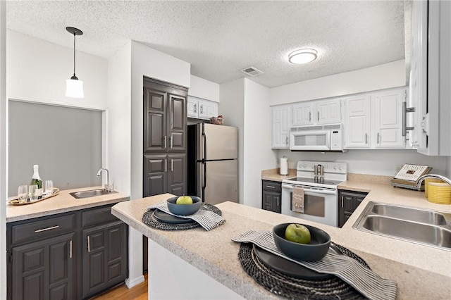 kitchen featuring white appliances, light hardwood / wood-style flooring, hanging light fixtures, and sink