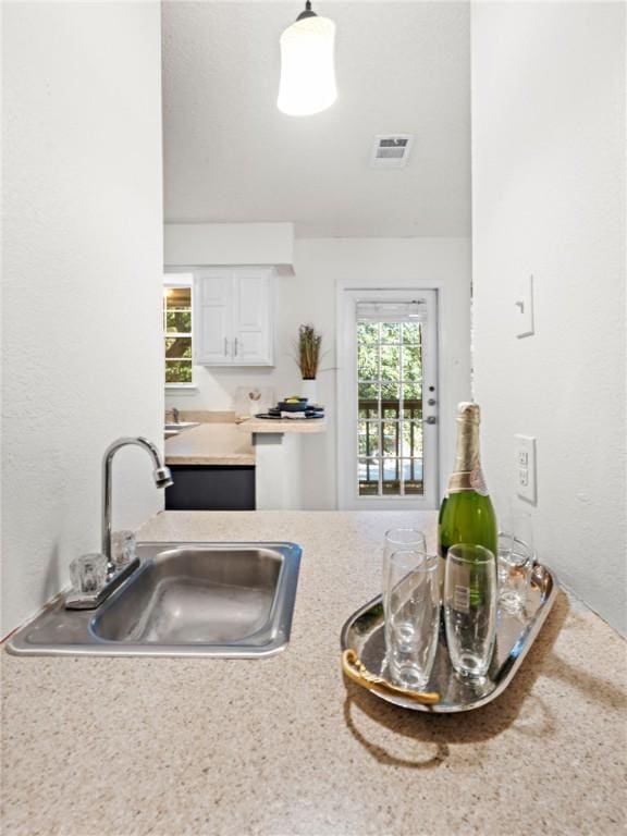 kitchen featuring white cabinetry, sink, and pendant lighting