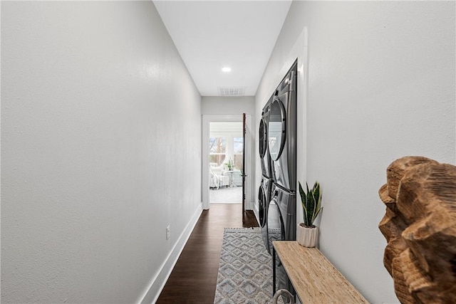 hall featuring stacked washer and clothes dryer and dark wood-type flooring