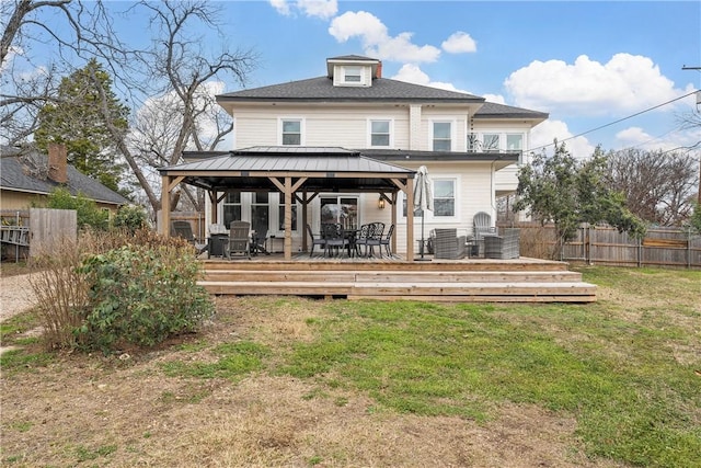 rear view of property featuring a gazebo, a deck, and a lawn