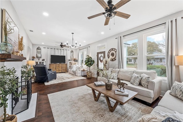 living room featuring ceiling fan with notable chandelier and dark hardwood / wood-style flooring